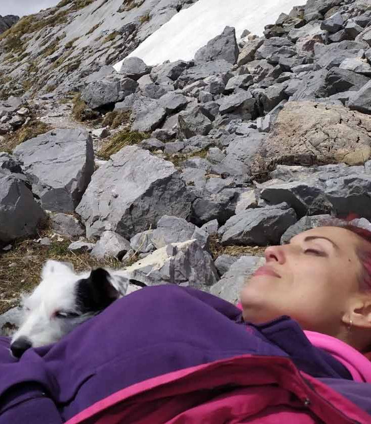 Educadora canina descansando en la montaña junto a su perra